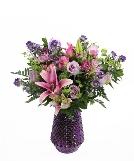 Fragrant and abundant, this design in a palette of purples and pinks features fragrant pink Oriental lilies, roses and more in a purple vase.  