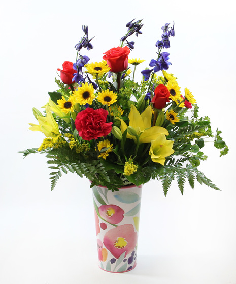 A striking mix of Asiatic lilies, delphinium, carnations, and viking poms, accented with seasonal touches arranged in a tall botanic pail.