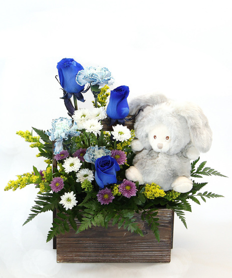 Our New Arrival bouquet is available in pink or blue tones, this design comes nestled in a wooden box, accompanied by a plush bunny. 