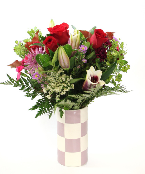 Fragrant and abundant, this design in a palette of purples and pinks features fragrant pink Oriental lilies, roses and more in a purple and white blocked vase.  